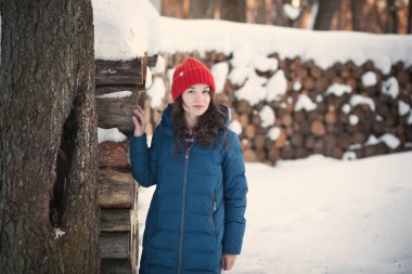 Kış ormanlarındaki alpaka yününden sıcak bir şapka takmış güzel genç kız.