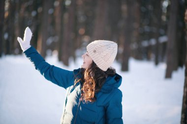 Kış ormanındaki alpaka yününden sıcak bir şapka takmış güzel genç kız. Örgü.