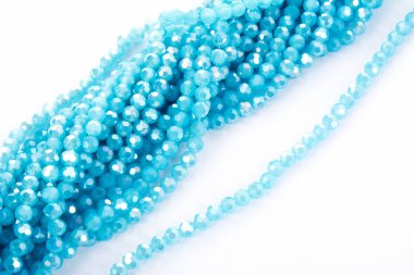 Güzel açık mavi cam parıltılı kristal boncuklar beyaz arka planda. Küçük boncuklu mücevherler için kullan
