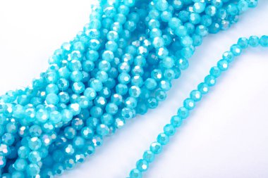 Güzel açık mavi cam parıltılı kristal boncuklar beyaz arka planda. Küçük boncuklu mücevherler için kullan