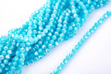 Güzel açık mavi cam parıltılı kristal boncuklar beyaz arka planda. Küçük boncuklu mücevherler için kullan