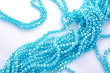 Güzel açık mavi cam parıltılı kristal boncuklar beyaz arka planda. Küçük boncuklu mücevherler için kullan
