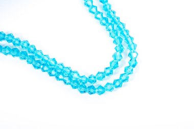 Güzel açık mavi cam parıltılı kristal boncuklar beyaz arka planda. Küçük boncuklu mücevherler için kullan