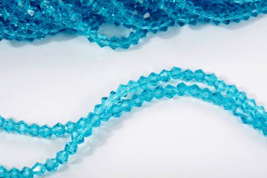 Güzel açık mavi cam parıltılı kristal boncuklar beyaz arka planda. Küçük boncuklu mücevherler için kullan