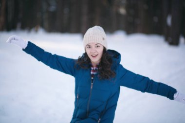 Kış ormanındaki alpaka yününden sıcak bir şapka takmış güzel genç kız. Örgü.