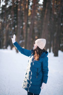Kış ormanındaki alpaka yününden sıcak bir şapka takmış güzel genç kız. Örgü.