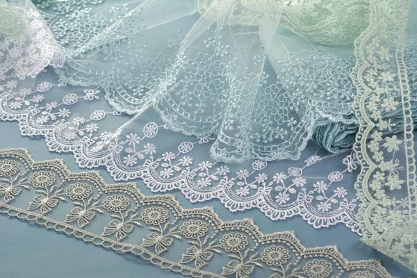 pile of blue, white, gray gentle guipure, lace fabric on blue background. use for atelier