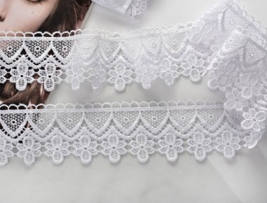 Beyaz yumuşak iplik bantları, hafif arka planda güzellik danteli kumaş. Elastik malzeme. Atıcı ve nakış dükkanı için kullanılıyor.