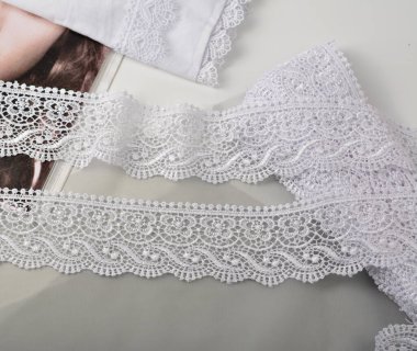 Beyaz yumuşak iplik bantları, hafif arka planda güzellik danteli kumaş. Elastik malzeme. Atıcı ve nakış dükkanı için kullanılıyor.