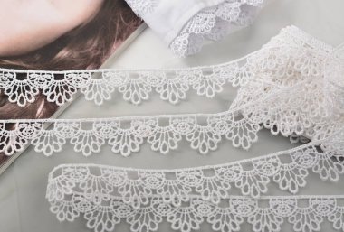 Beyaz yumuşak iplik bantları, hafif arka planda güzellik danteli kumaş. Elastik malzeme. Atıcı ve nakış dükkanı için kullanılıyor.