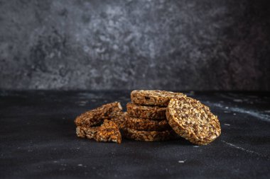 Ayçiçeği tohumlarından karamel fıstık şekeri ve susam tohumları ve keten tohumlu ve koyu beton arkaplanlı fitness kurabiyeleri..