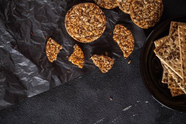 Ayçiçeği tohumlarından karamel fıstık şekeri ve susam tohumları ve keten tohumlu ve koyu beton arkaplanlı fitness kurabiyeleri..