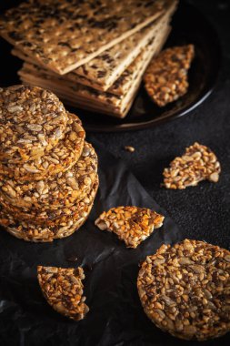 Ayçiçeği tohumlarından karamel fıstık şekeri ve susam tohumları ve keten tohumlu ve koyu beton arkaplanlı fitness kurabiyeleri..