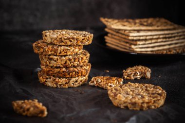 Ayçiçeği tohumlarından karamel fıstık şekeri ve susam tohumları ve keten tohumlu ve koyu beton arkaplanlı fitness kurabiyeleri..