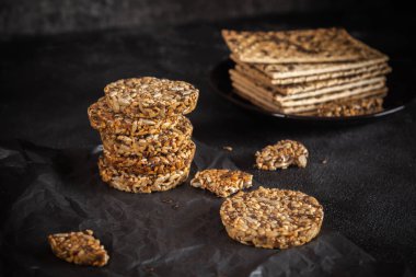 Ayçiçeği tohumlarından karamel fıstık şekeri ve susam tohumları ve keten tohumlu ve koyu beton arkaplanlı fitness kurabiyeleri..
