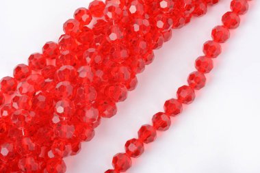 Beyaz arka planda güzel kırmızı cam kristal boncuklar. Küçük boncuklu mücevherler için kullan