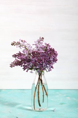 Minimum kompozisyon, arka planda cam şişedeki leylak çiçekleri. Çiçekli bahar dokusu