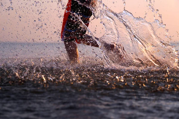 The boy runs on the water spraying feet