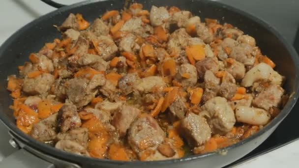 In a large frying pan, meat and vegetables are fried in Italian. Bon appetit. Angle lens. Fried meat with onions, carrots and spices. — Stock Footage In a large frying pan, meat and vegetables are fried in Italian. Bon appetit. Angle lens. Fried meat with onions, carrots and spices. Royalty Free Stock Footage