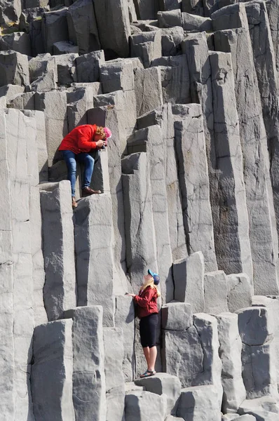 Unbekannte fotografieren Touristen am Strand von Reynisdrangar in Island. — Stockfoto