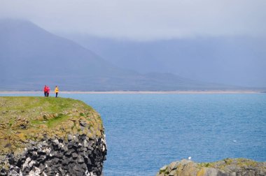 Kimliği belirsiz turist Gatklettur Stone, İzlanda yakınındaki cliff ayakta.