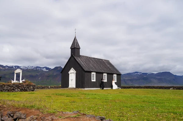 Oidentifierade brudparet står framför berömda svarta kyrkan i Budir, Island. — Stockfoto