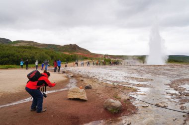 İzlanda'daki Strokkur Geysir kimliği belirsiz turist alarak resmi