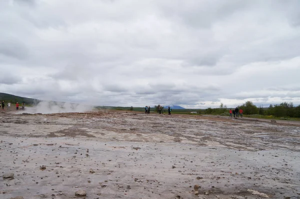 Unidentified tourists waiting for eruption of Strokkur Geysir in Iceland. — Stock Photo, Image