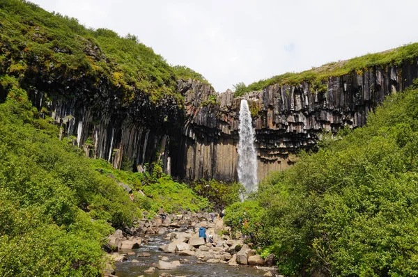 Niezidentyfikowanych turystów umiejscowienia na skale w Svartifoss w Islandii. — Zdjęcie stockowe