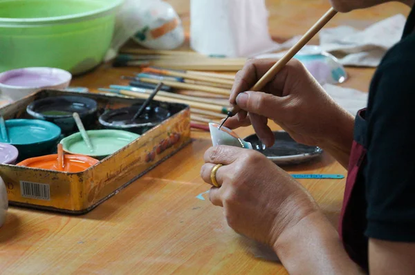 Gros plan d'un potier faisant dessiner une bite à une femme sur un bol blanc, Thaïlande . — Photo
