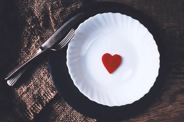 Сервировка стола с красным сердцем в тарелке — стоковое фото