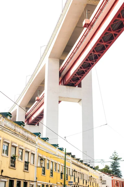 A ponte 25 de Abril sobre os edifícios da cidade — Fotografia de Stock