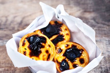 Pasteis de Nata - tatlı curstard ile kremsi yumurta tart, ahşap arka plan üzerinde siyah kabuk ve şeker tozu. Pasteis de Belem pasta