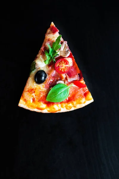 Pizza slice with Pepperoni, melting cheese and olives served at a pizzeria or restaurant