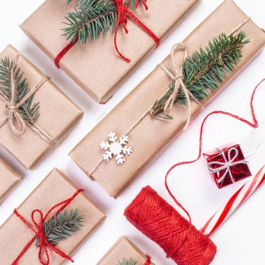 Festival kutular olarak Noel hediyesi zanaat pape sarılı beyaz arka plan üzerinde şerit yay ve köknar ağacı dalı ile