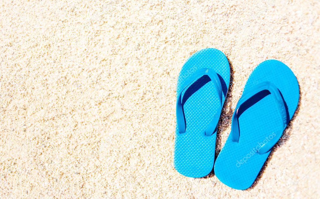 Summer holiday beach background with flip flops on a tropical beach. Slippers on a  sand with copyspace