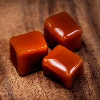 Organic caramel candies and caramel sauce on wooden background, Golden Butterscotch toffee caramel clipart