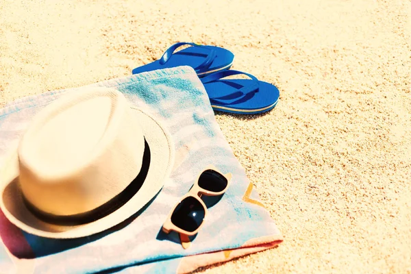 Yaz eğlenceli saat ve aksesuarları bir kum plaj üzerinde. Mavi sandalet flip flop, şapka, güneş gözlüğü ve havlu, vintage görüntü tonda
