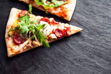 Sıcak pizza dilim eritilmiş mozzarella peyniri ve domates siyah beton zemin üzerine. Pizza hazır yemek için boşaltmak