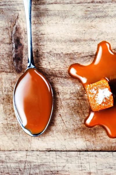 Homemade  Caramel sauce flowing on caramel candies on wooden  board