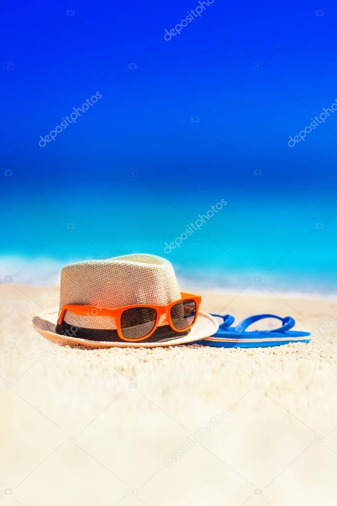 Flip-flops, beach hat, sun glasses on the sand. Summer vacation concept. Summer fun time and accessories on tropical beac