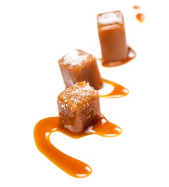 Karamel parçalar ve beyaz arka plan üzerinde izole deniz tuzu tuzlu. Altın Karamelalı şekerleri karamel. Toffees, makro