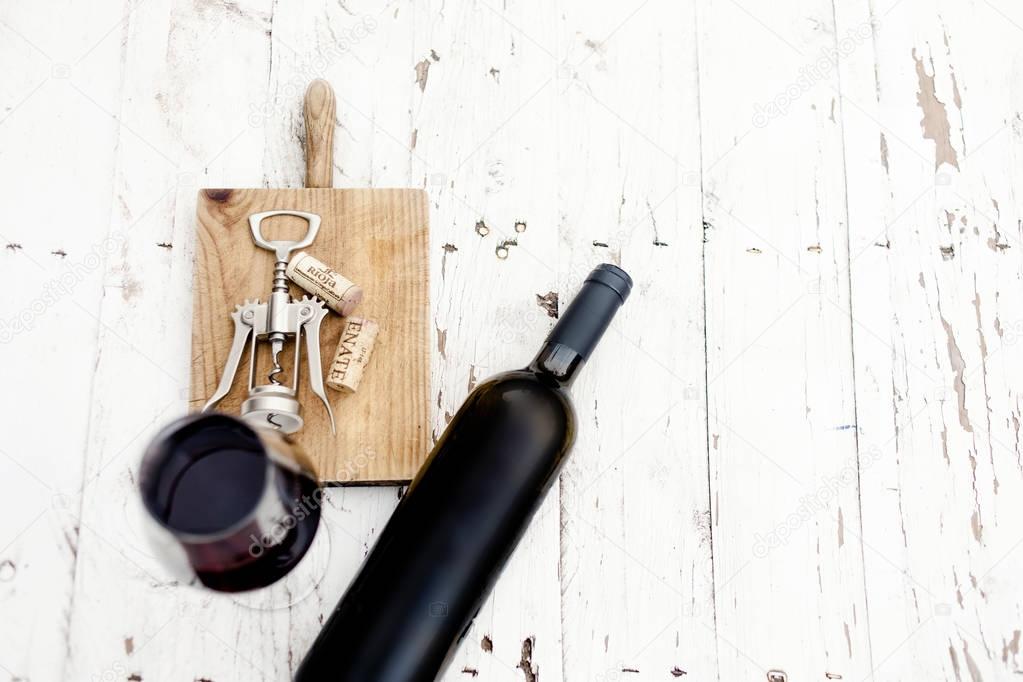  A glass of red wine, bottle, corkscrew  and wine corks on rustic white wooden background, copyspsce. Wine tasting concep
