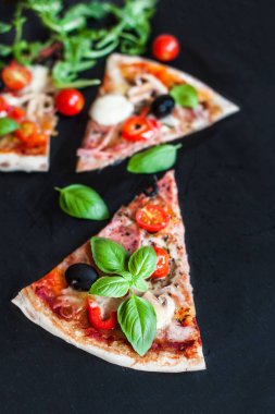 Pizza Margarita domates, fesleğen yaprağı ve peynir ile. Margherita Pizza siyah taş zemin üzerine en iyi kopya alanı görünümüyle.