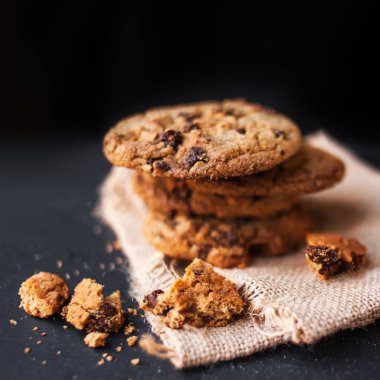 Çikolatalı kurabiye metin için yer ile koyu arka plan üzerine yığını. Choco cookie siyah arduvaz gemide keten peçete, boşluk ile seçici odak