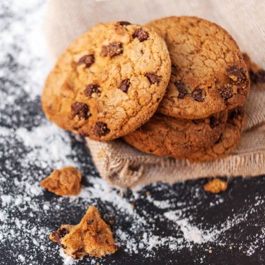 Çikolatalı kurabiye ile koyu arka plan üzerinde metin için yer. Choco cookie siyah arduvaz kurulu ile un, boşluk ile seçici odak keten peçete üzerine