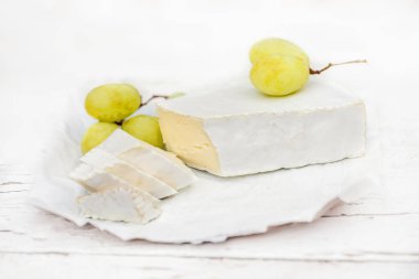 Taze Brie peyniri dilimleri ve üzüm beyaz rustik ahşap oyun tahtası üzerinde. Peynir Brie türü. Camembert peyniri.