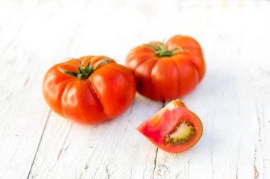 Büyük kırmızı taze domates rustik tarzı, düz eski bir ahşap masa üzerinde yatıyordu