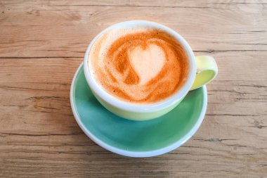 Kalp desenli rustik ahşap masa arka plan, üst üzerinde renkli bir fincan kahve vie