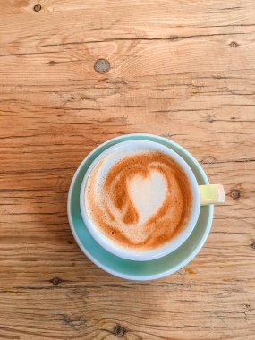 Kalp desen köpük rustik ahşap masa arka plan, üst üzerinde mavi bir fincan kahve vie
